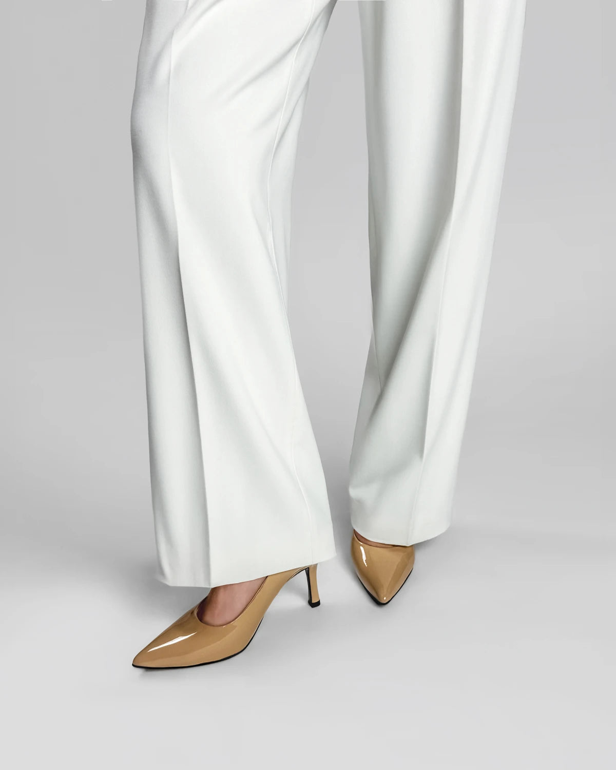 White pants with beige high-heeled shoes on a gray background