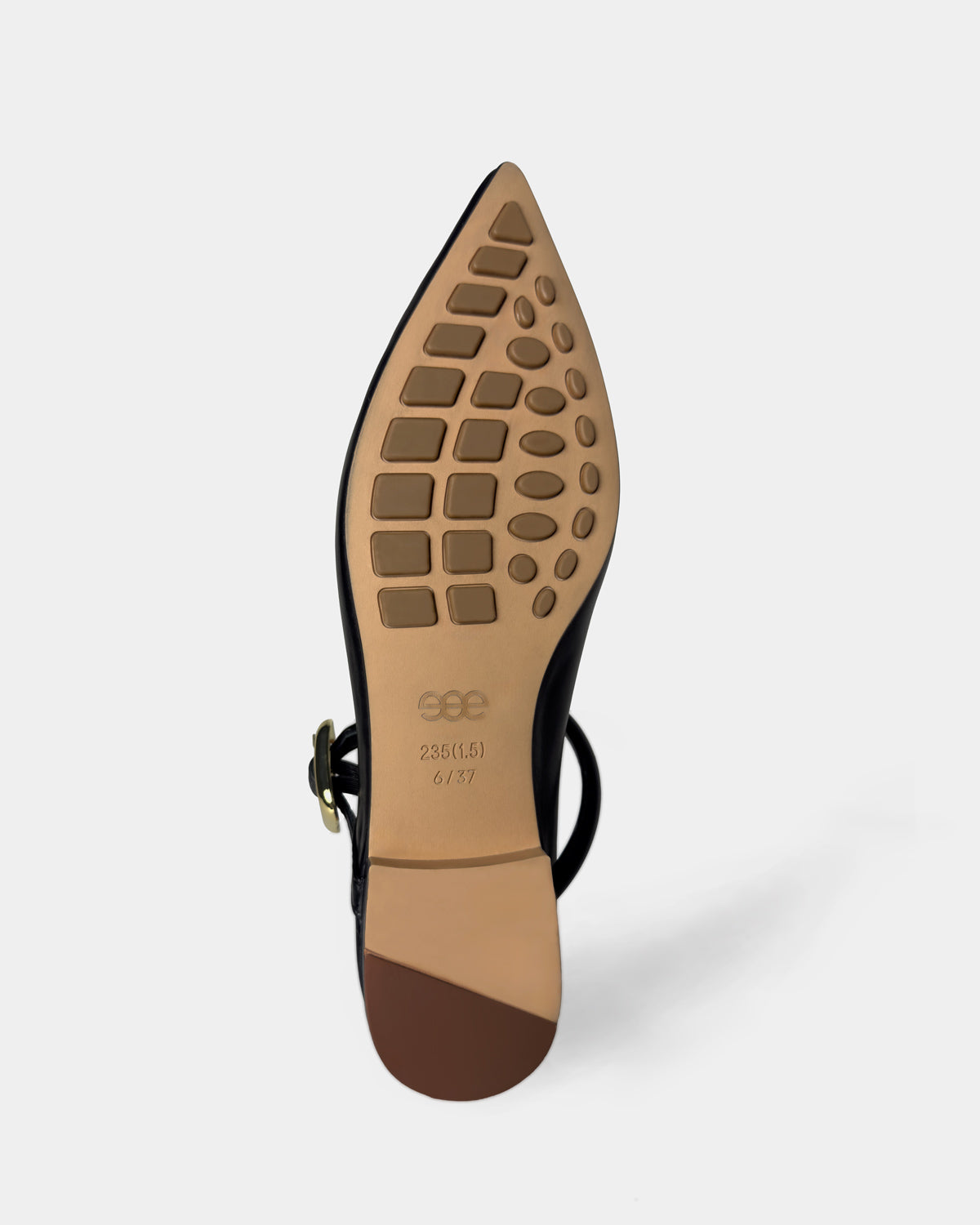 The sole of a black pointed-toe flat shoe with an ankle strap, showing a tan rubberized tread pattern.