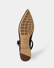 The sole of a black pointed-toe flat shoe with an ankle strap, showing a tan rubberized tread pattern.