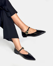 Black pointed-toe Mary Jane flats with a gold buckle strap
