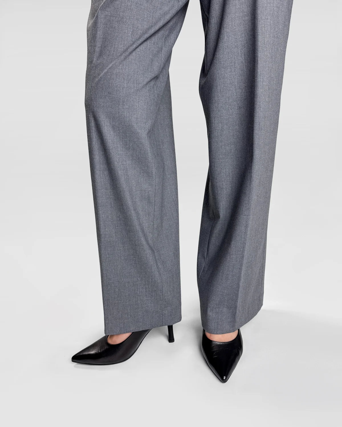 Gray pants worn with black high-heeled shoes on a white background