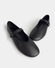 side view of a pair of black leather Mary Jane ballet flats with single strap and small buckle on the light grey background