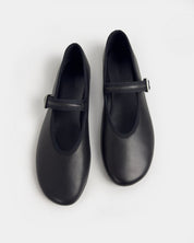 A pair of black leather ballet flats with a single strap and a small silver buckle, shown from a top-down view on a light gray background.