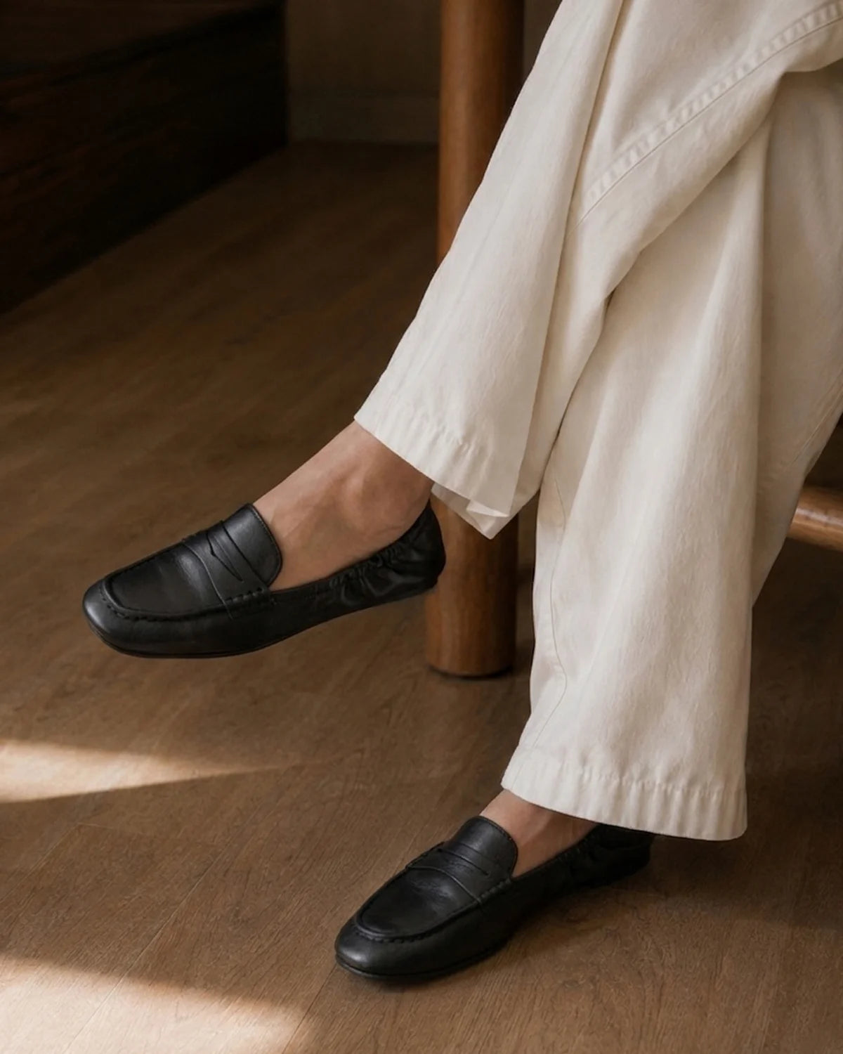 a person sitting somewhere comfortably in white pants and black sofe loafers