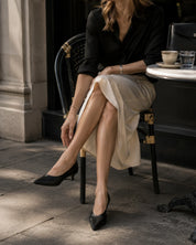 a woman sitting in a cafe in elegant outfit and black kitten heel pumps