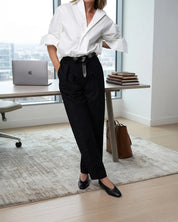 Woman wearing a white shirt, black pants and black flats in an office setting