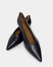 A pair of black leather pointed-toe pumps with a brown interior, displayed on a clean light gray background.