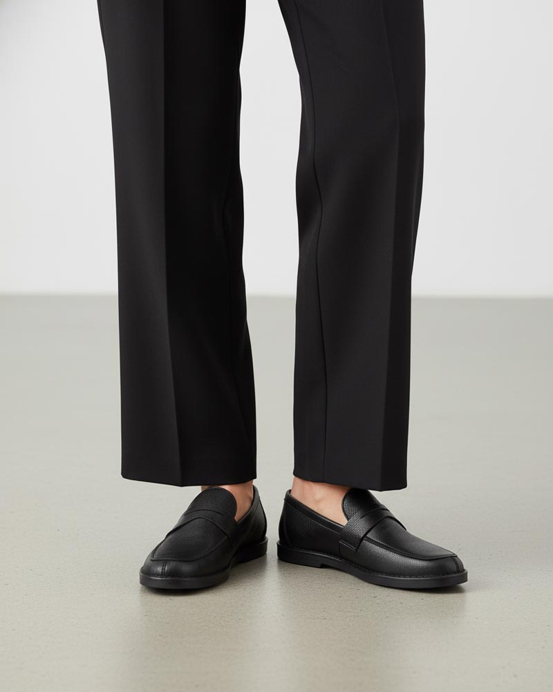 Model wearing black leather penny loafers 