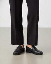 Model wearing black leather penny loafers 