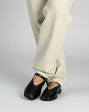 Model wearing Mary Jane Shoes in black leather with casual pants.