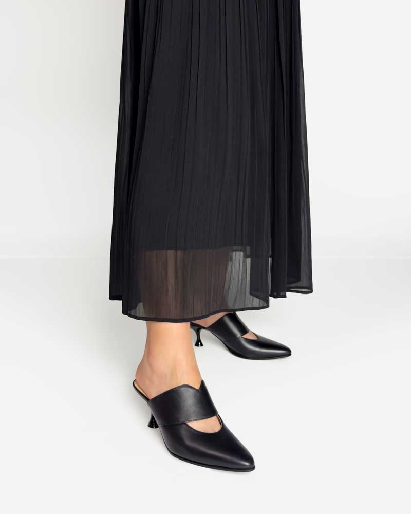 model styling black mules kitten heels with skirt