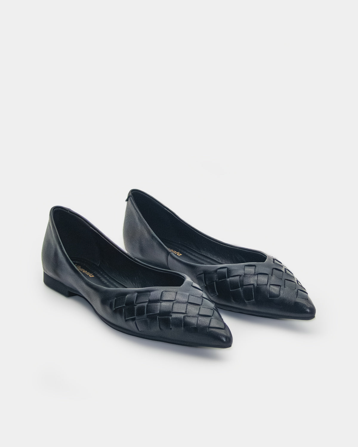 A pair of black leather pointed-toe flats with a woven pattern on the toe, shown on a light gray background.