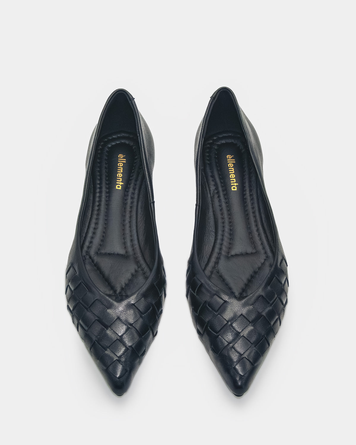 A pair of black pointed-toe flats with a woven leather pattern on the toe box, shown from a top-down view on a light gray background. The brand name 'ellementa' is visible in gold on the insoles.