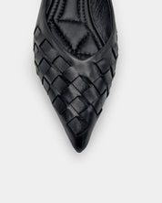 A close-up top-down view of a black leather pointed-toe flat shoe with a woven pattern on the toe box