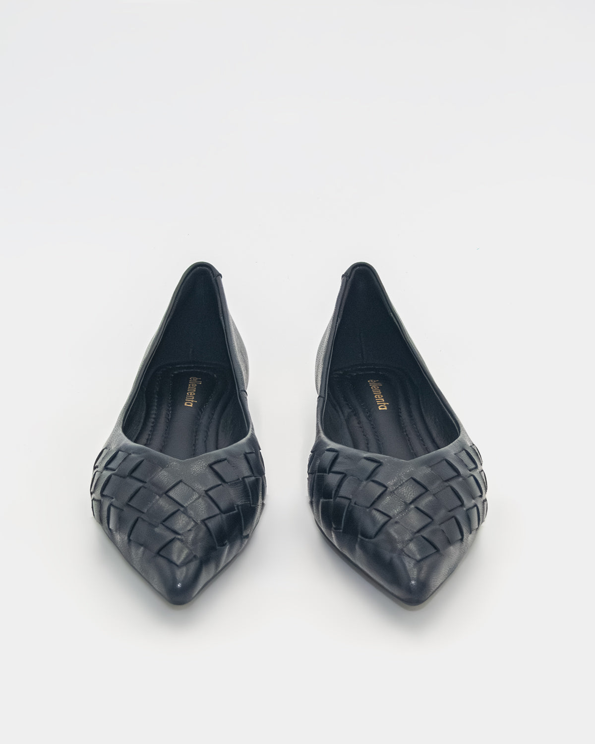 A pair of black pointed-toe flats with a woven leather upper, shown from a top-down view on a light gray background.