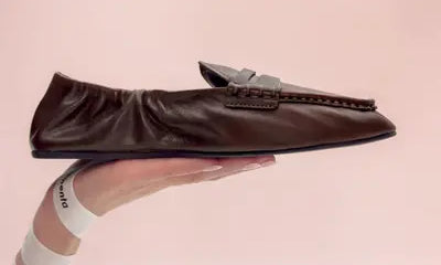 lightweight brown loafer hold by a hand
