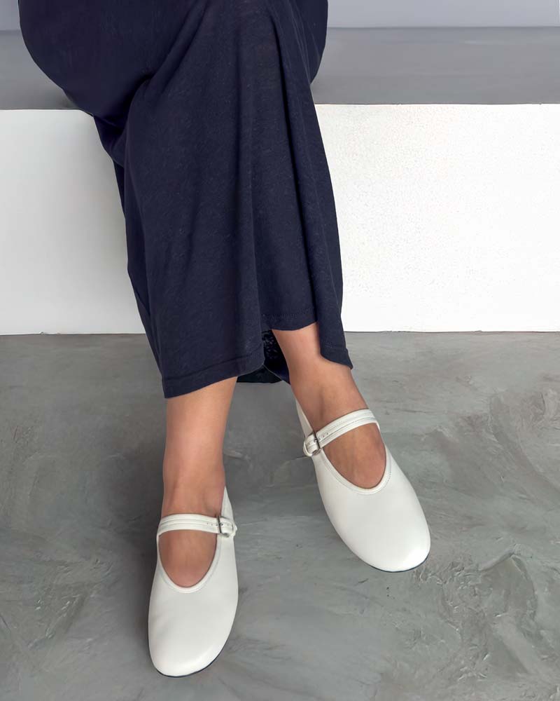 Model styling white ballet flats with strap with skirt