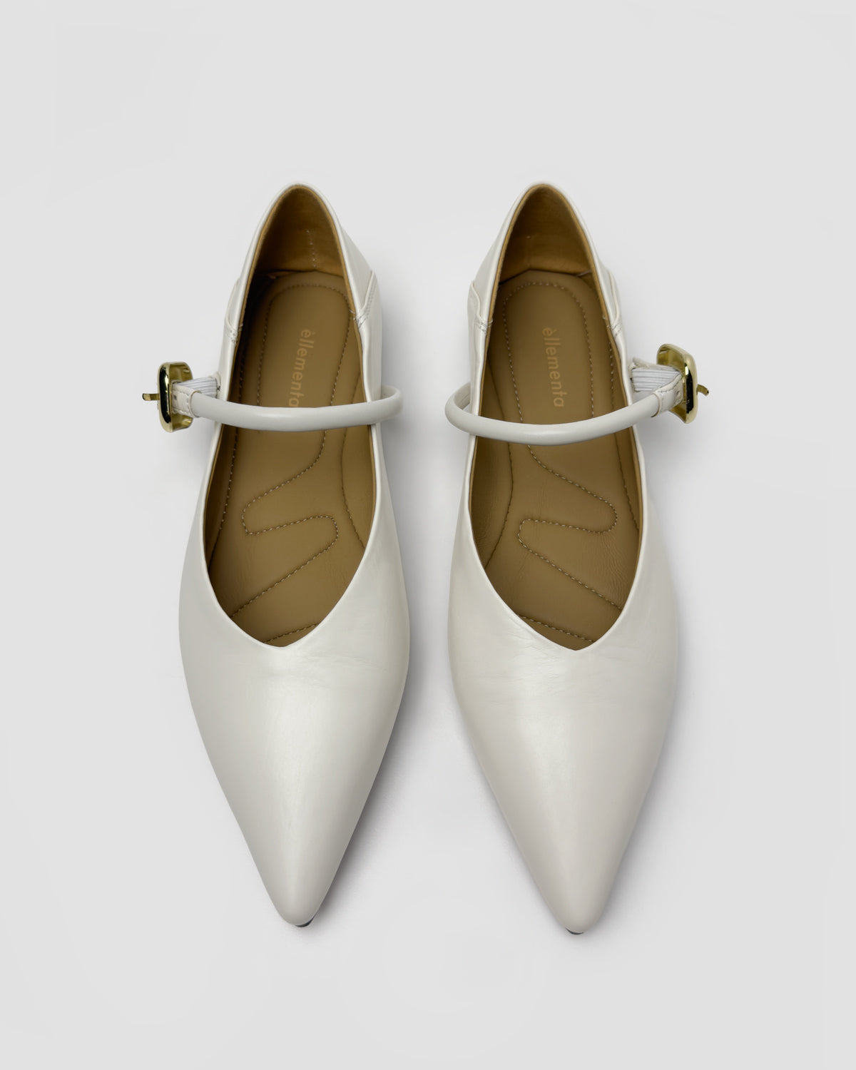 A pair of pointed-toe Mary Jane flats in a glossy off-white finish, featuring a thin strap with a small gold-tone buckle, photographed from a top-down angle on a light gray background.