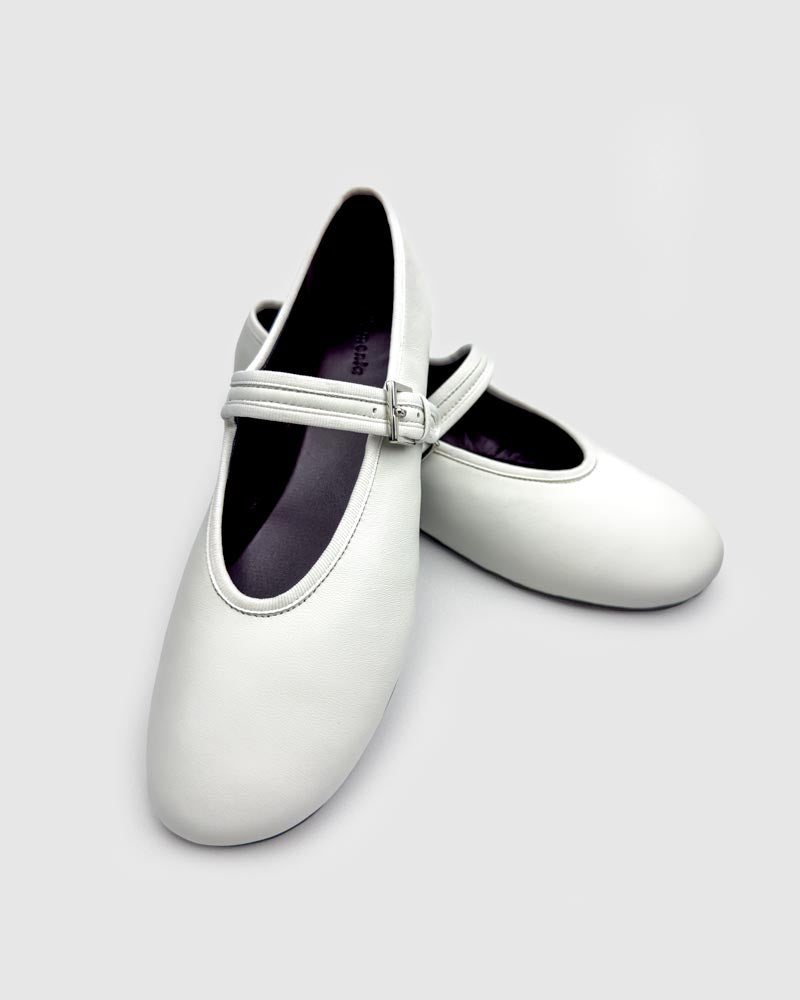 A pair of white ballet flats with strap in leather
