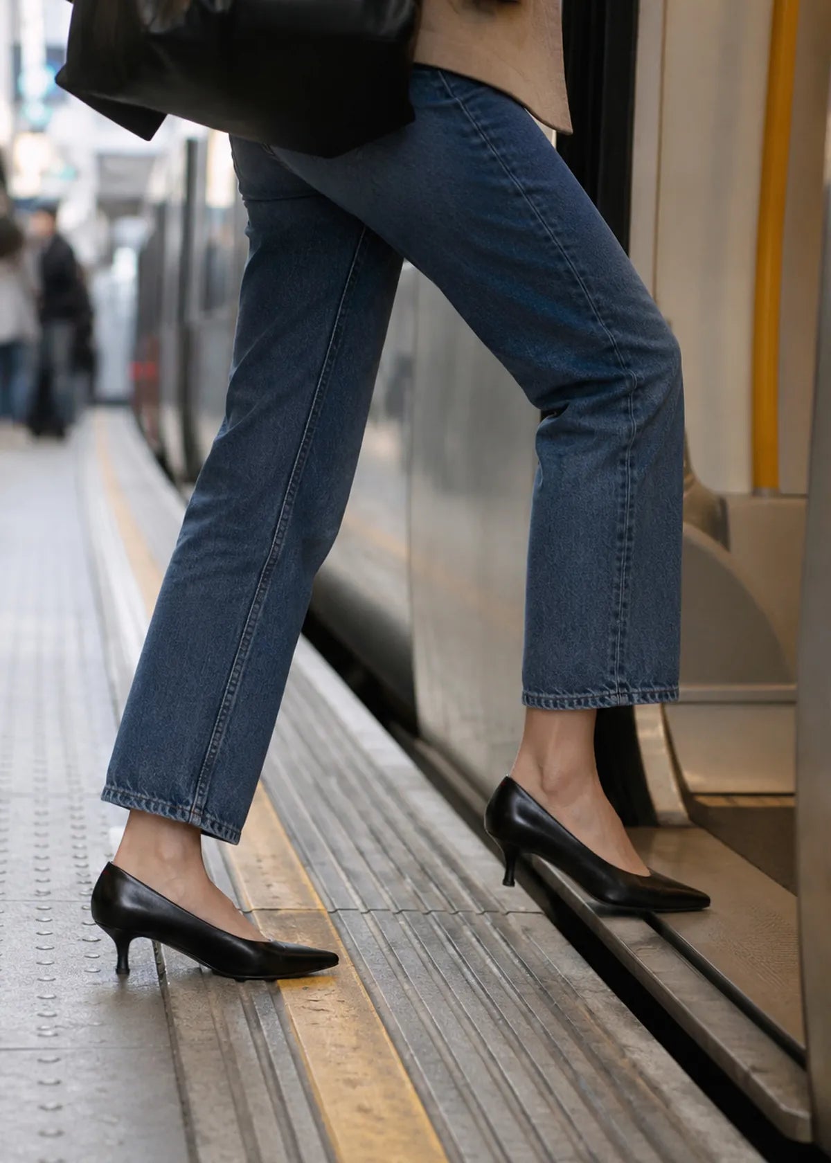 a woman is getting on the train in jeans and black kitten heel pumps